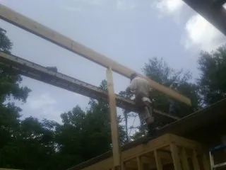 Carpenter setting a ridge beam over a new addition frame — Ice Dam Removal by Roofing Brothers in Mico