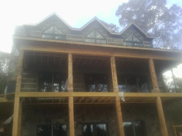 Dormers and porch framing on a large log home under construction — Roof Coating work by our crew in Mico