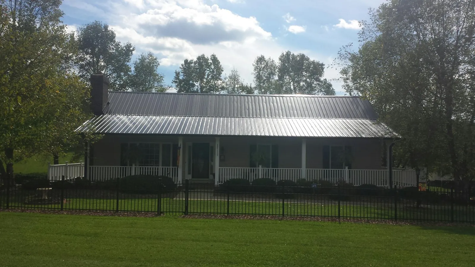 Gray metal roof on a brick ranch with a full width front porch — Gutter Guard Installation work by our crew in Mico