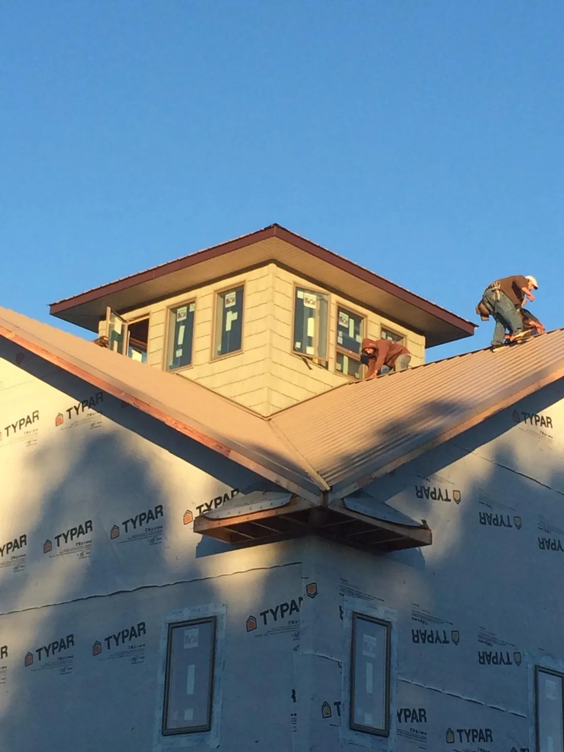Roofers working around a rooftop cupola on a new metal roof at sunset — Roof Waterproofing in Mico by Roofing Brothers